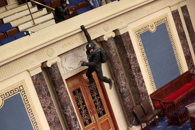 Seorang protestan terliaht bergelantungan dari balkon Ruang Senat