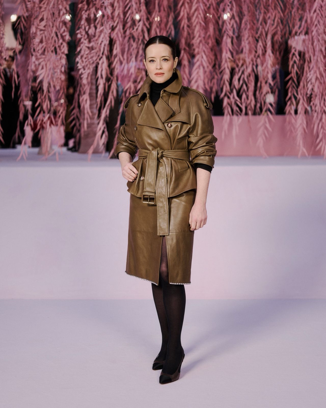 Claire Foy menggunakan trench coat bewarna coklat tua dengan bahan kulit