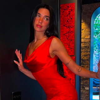 Dua Lipa Tampil Memesona Memakai Slipdress Sutra Merah dari Ferragamo di Malam Musim Panas