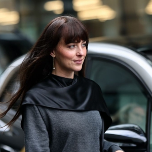 Dakota Johnson Tampil Manis dan Keren dengan Platform Boots Kulit dan Cape Sweater