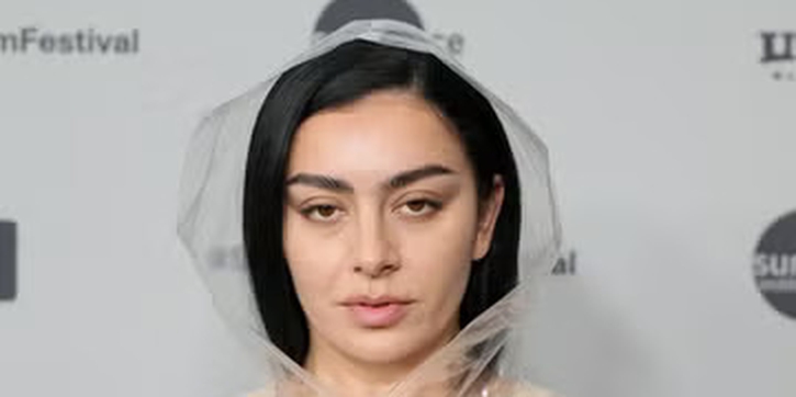 Charli XCX Kenakan Terusan Nude dengan Ponco Transparan Berhiaskan Renda