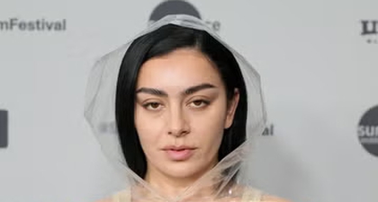 Charli XCX Kenakan Terusan Nude dengan Ponco Transparan Berhiaskan Renda